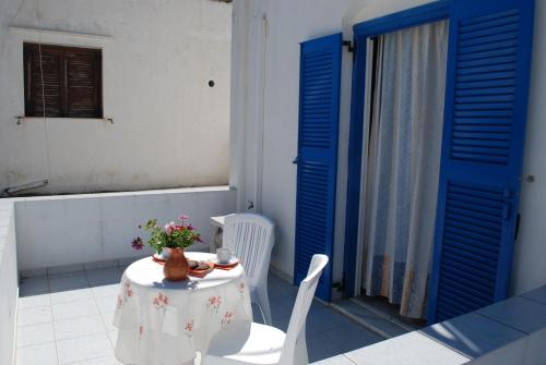 una mesa y sillas en una habitación con puertas azules en To Steno, en Kamarai