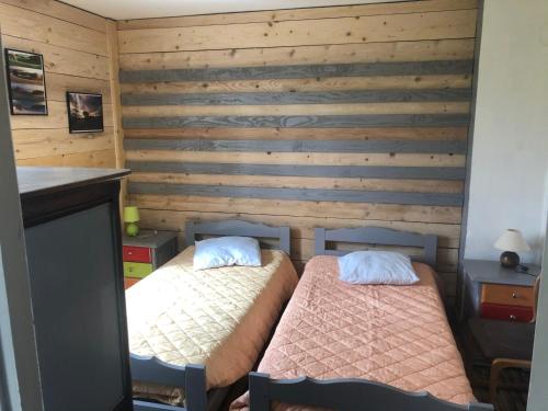 two beds in a room with wooden walls at La coopé de maurines in Maurines