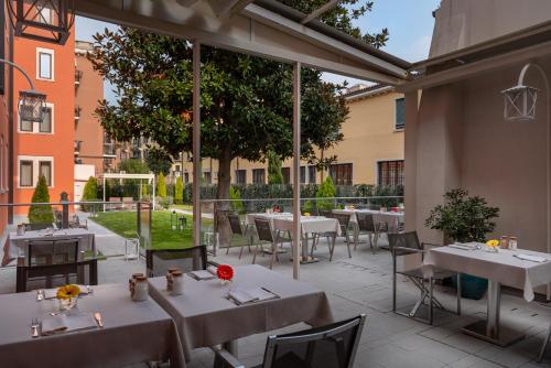 a restaurant with white tables and chairs in a courtyard at Carnival Palace - Venice Collection in Venice