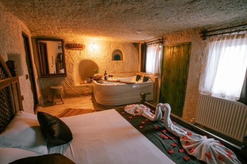 Un baño con una cama, una bañera y un lavabo. en Mia Cappadocia Cave Hotel, en Göreme