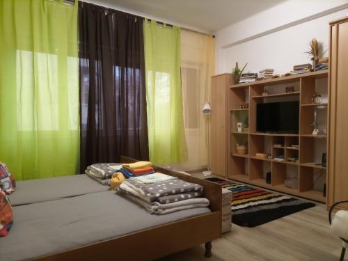 een slaapkamer met een bed met groene gordijnen en een tv bij Studio Apartment Corner in Rijeka