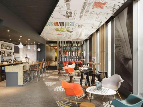 a restaurant with orange chairs and tables and a bar at ibis London Excel-Docklands in London