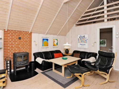 Elle comprend un salon doté d'un mobilier en cuir et d'une cheminée. dans l'établissement 6 person holiday home in Bl vand, à Blåvand