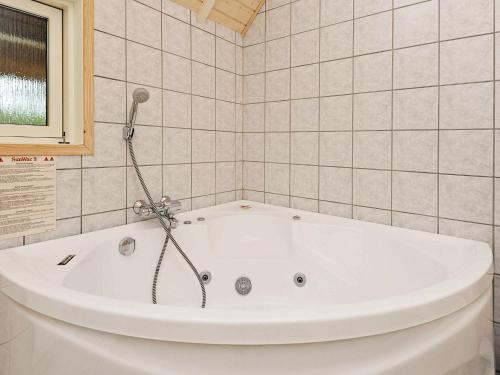 La salle de bains carrelée est pourvue d'une baignoire blanche. dans l'établissement 6 person holiday home in Bl vand, à Blåvand