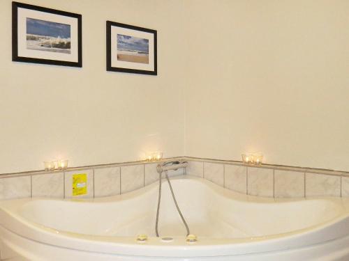 y baño con bañera y 2 cuadros en la pared. en 10 person holiday home in Harbo re, en Harboør