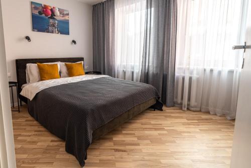 a bedroom with a bed with yellow pillows and a window at Lovely apartment in the city center in Kaunas