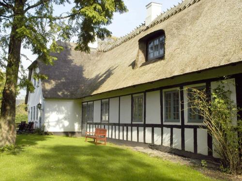 una casa vieja con un banco en el patio en 18 person holiday home in N rre Aaby en Føns