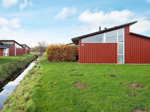 6 person holiday home in Bogense في بوجنسي: منزل احمر واجهه حمراء على ميدان عشبي