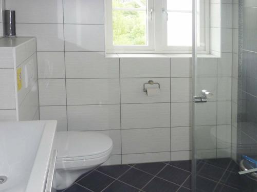 a white bathroom with a toilet and a window at Four-Bedroom Holiday home in Bygstad 1 in Bygstad