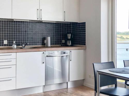 - une cuisine avec des placards blancs, un lave-vaisselle et une table dans l'établissement Holiday Home Banedæmningen II, à Hejls