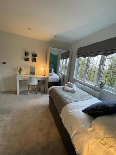 a bedroom with a bed and a desk and windows at Hinksey Heights in Oxford