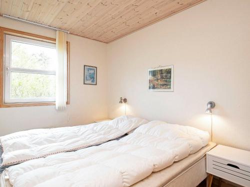 a large white bed in a room with a window at 6 person holiday home in Læsø-By Traum in Læsø