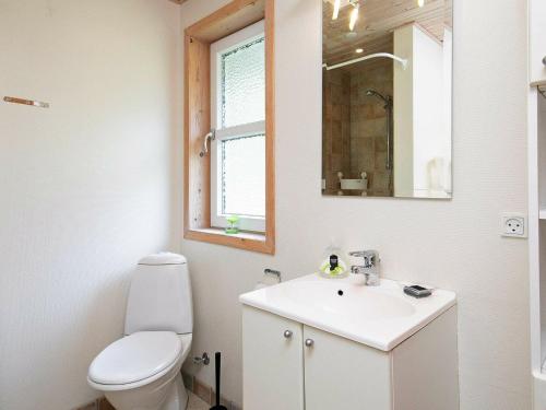 La salle de bains est pourvue de toilettes, d'un lavabo et d'un miroir. dans l'établissement Holiday home Læsø XXIV, à Læsø