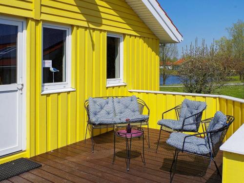 a group of chairs sitting on a deck with a yellow house at 12 person holiday home in Otterndorf in Otterndorf