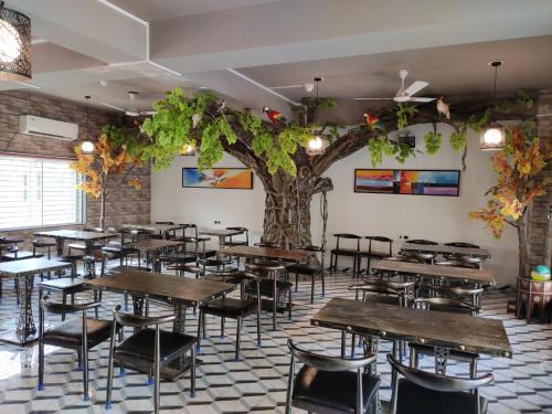 restauracja ze stołami, krzesłami i drzewem w obiekcie Healthville by WB Resorts w mieście Chandaka