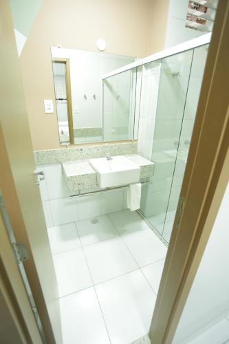 ein weißes Badezimmer mit einem Waschbecken und einem Spiegel in der Unterkunft Valen Porto Hotel São Luís in São Luís