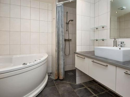 ein weißes Badezimmer mit einer Badewanne und einem Waschbecken in der Unterkunft Three-Bedroom Holiday home in Rømø 5 in Kongsmark