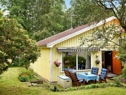 a yellow house with a table and chairs in the yard at 4 person holiday home in LYSEKIL in Brastad