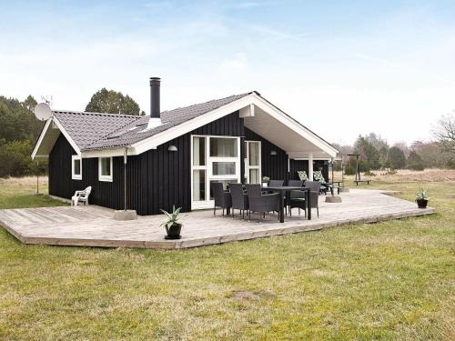 a black house with a deck with a table and chairs at 5 person holiday home in lb k in Ålbæk