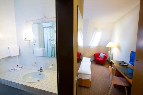 a bathroom with a sink and a red chair at Hotel Marienlinde in Telgte