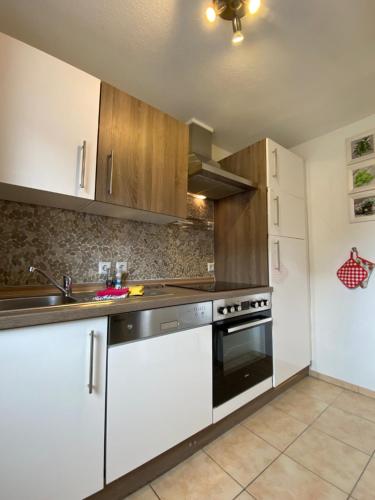 a kitchen with white cabinets and a sink and a stove at Macke`s Ferienwohnungen in Hahnenklee-Bockswiese