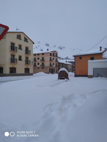 a parking lot covered in snow with buildings in the background at Hotel Herranz in Alcoroches