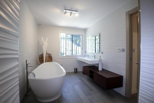 une salle de bain blanche avec une baignoire et un lavabo dans l'établissement Magnifique Villa avec piscine à débordement à Maussane les Alpilles, à Maussane-les-Alpilles