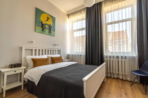 a bedroom with a bed and two windows at Beautiful apartment in the heart of Kaunas in Kaunas