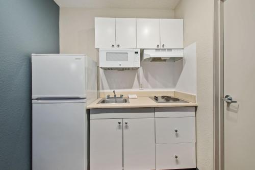 a small kitchen with white cabinets and a refrigerator at Extended Stay America Suites - Miami - Airport - Blue Lagoon in Miami