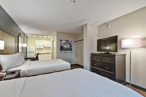 a hotel room with two beds and a flat screen tv at Extended Stay America Suites - Miami - Airport - Blue Lagoon in Miami