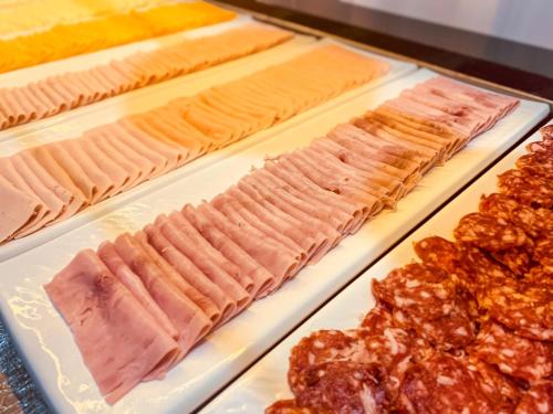 a display case with different types of meats and other foods at Ouro Minas Hotel Belo Horizonte, Dolce by Wyndham in Belo Horizonte