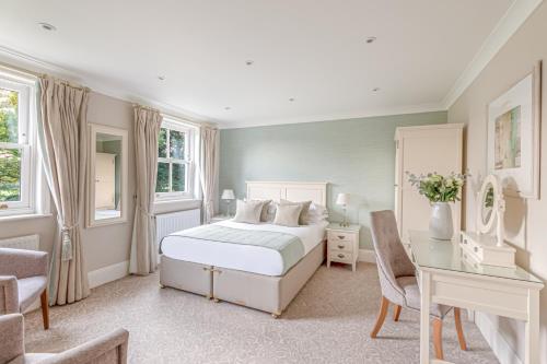 a bedroom with a white bed and a desk at Bartley Lodge Hotel in Lyndhurst