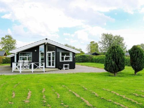 Øster Hurupにある6 person holiday home in Hadsundの庭にパティオが付いた黒いコテージ