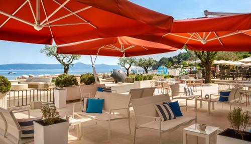 a patio with tables and chairs and umbrellas at Hotel Mediteran - Liburnia in Mošćenička Draga