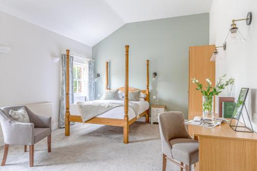 a bedroom with a four poster bed and a desk at Bartley Lodge Hotel in Lyndhurst