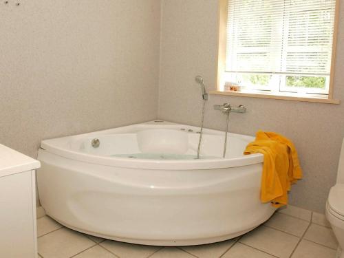 a white bath tub in a bathroom with a window at Modern Holiday Home in Aakirkeby with Sauna in Vester Sømarken