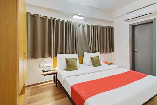 a bedroom with a large bed with a red blanket at Kanak Beacon Hotel - Ashram Road Ahmedabad in Ahmedabad