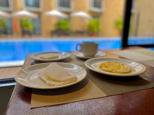 a table with two plates of breakfast food on it at Bessa Beach Hotel in João Pessoa