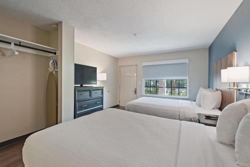 a hotel room with two beds and a flat screen tv at Extended Stay America Suites - Miami - Airport - Blue Lagoon in Miami