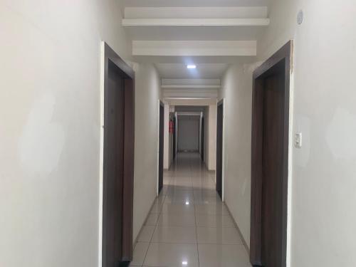 a hallway with white walls and a row of doors at JK Rooms 147 Lions - Koradi Nagpur in Nagpur