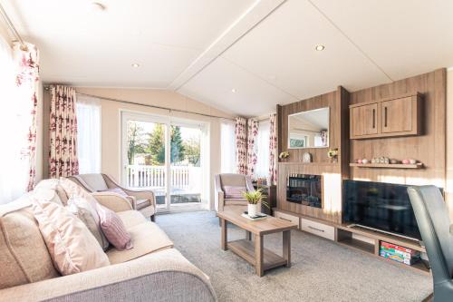 uma sala de estar com um sofá e uma televisão em Lakeshore Lodge with Hot Tub em Pocklington