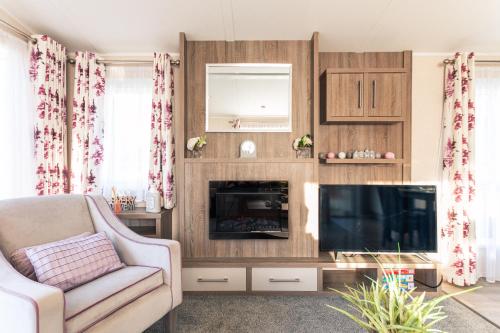 Lakeshore Lodge with Hot Tub في بوكلينجتون: غرفة معيشة مع تلفزيون وأريكة وكرسي