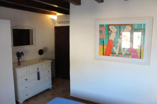 a bedroom with a dresser and a painting on the wall at Pesca 2 in Cala de Sant Vicenc