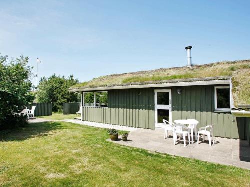 a green house with a table and chairs in a yard at 6 person holiday home in Pandrup in Rødhus