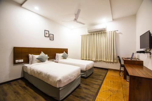 a hotel room with two beds and a flat screen tv at Skyla Serviced Apartments in Hyderabad