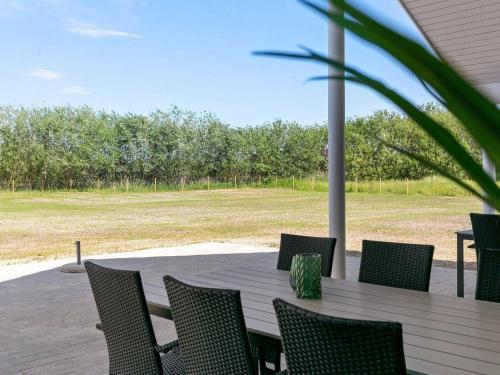 a table and chairs on a patio with a field at Holiday Home in Zealand with Private Pool in Marielyst