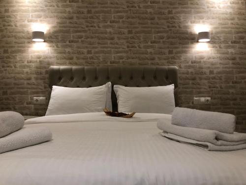 a large bed with white pillows and a brick wall at Luxury Plateia Rooms in Perea