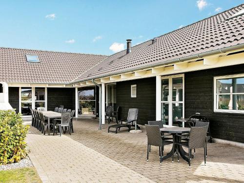 a patio with tables and chairs in front of a house at 18 person holiday home in Idestrup in Marielyst