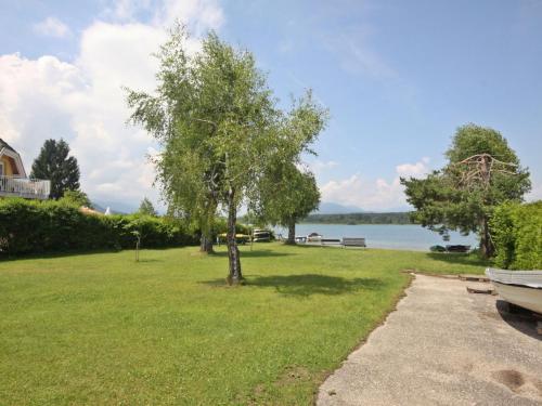 a park with a tree and a boat on the grass at Holiday Home Seehaus Blue Faak by Interhome in Faak am See
