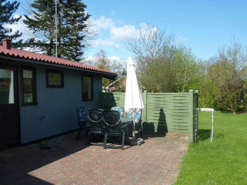a patio with two chairs and an umbrella and a fence at 6 person holiday home in Str by in Strøby